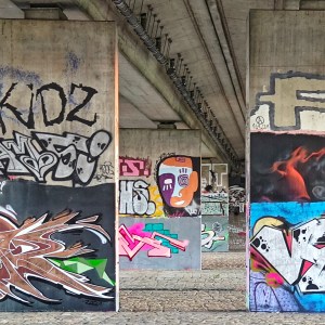 Graffiti: Teilansicht der Brückengalerie mit dem bunten Avangardekopf im Hintergrund