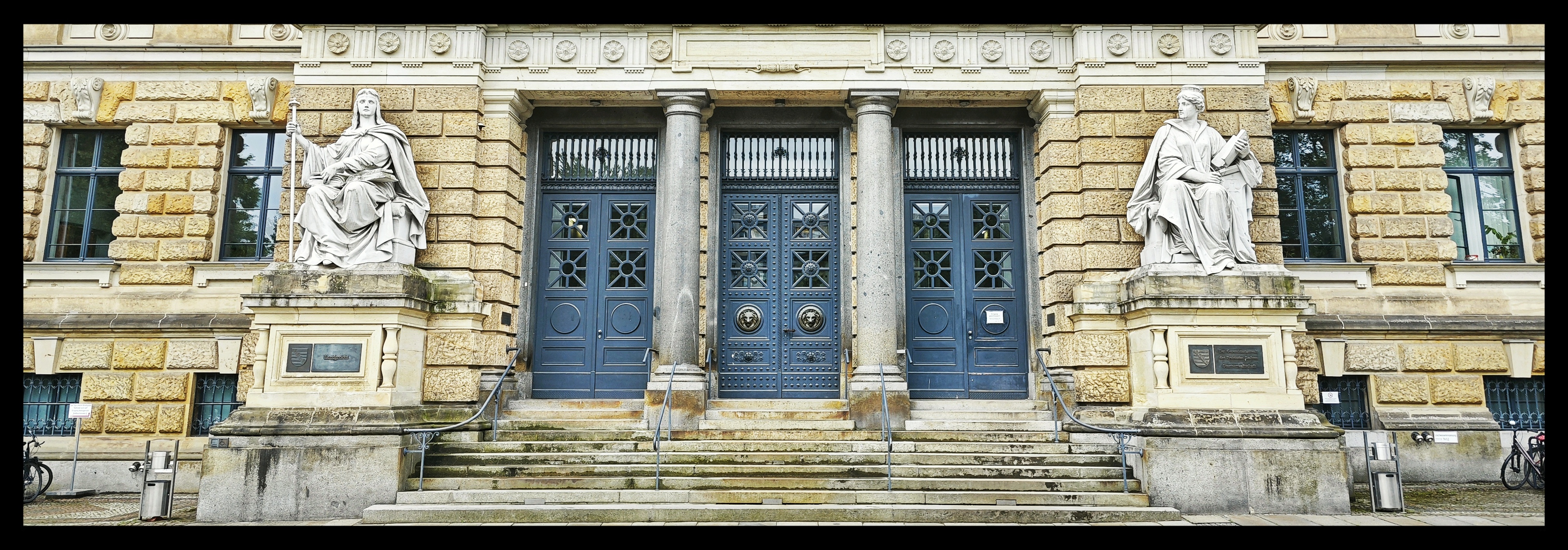 Das Portal des Landgerichts Dresden in der Totalen mit jeweils einer Statue der gesetzgebenden Justitia und der vollziehenden Justitia an jweils einer Seite der breiten Treppe zum dreifach geteilten Portal.